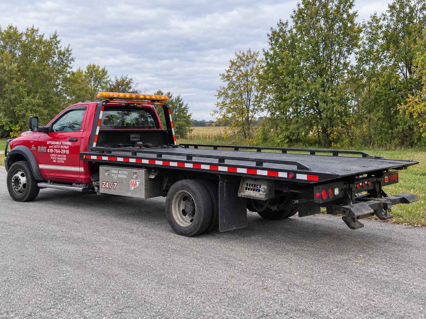 Illustrative daytime view of the company's red RAM tow truck with an empty flatbed